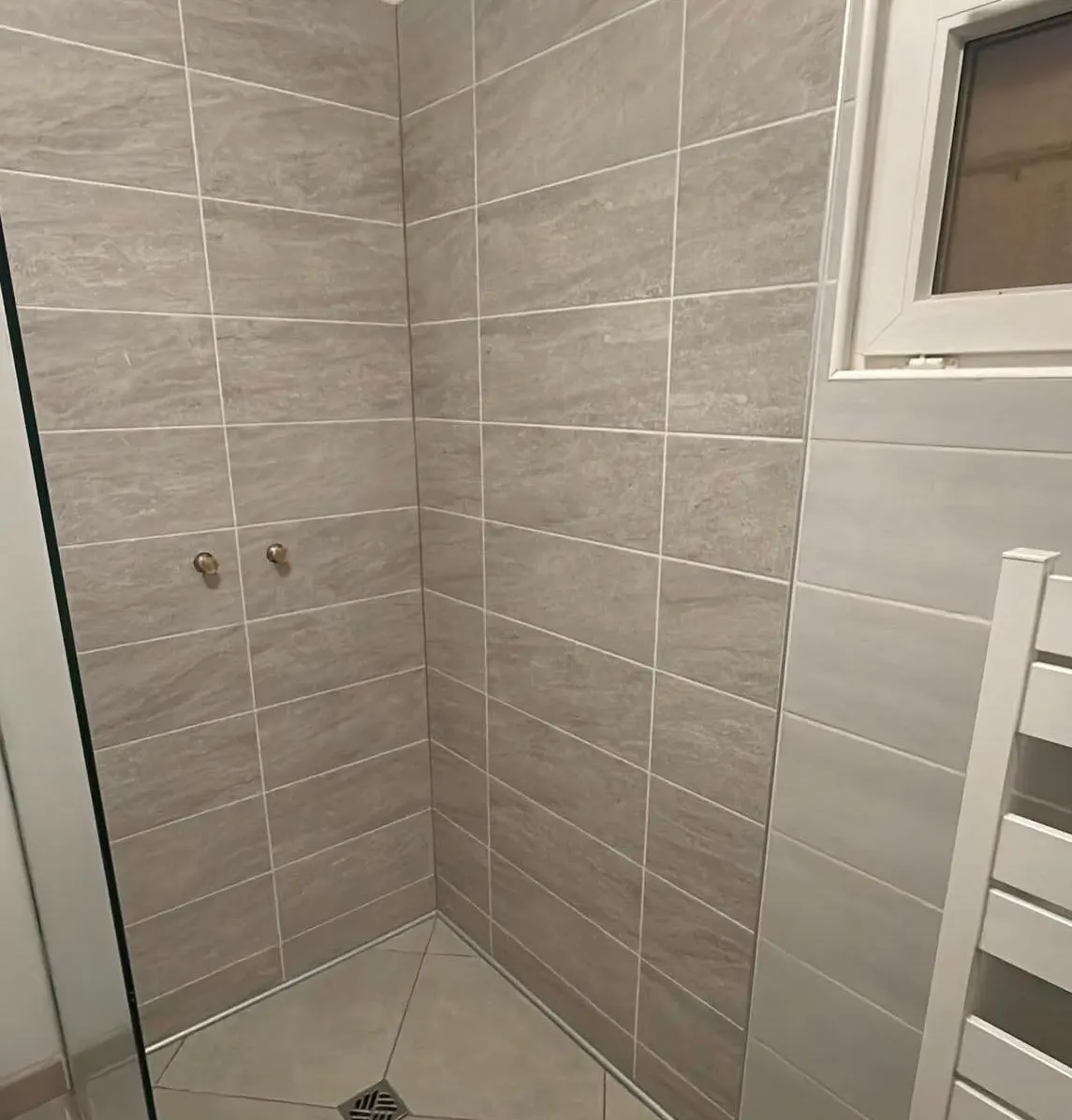 Douche à l'italienne : murs en faïence grise posée à joints alternés, sol découpé en pente vers la bonde