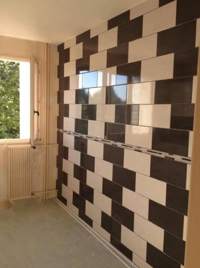 Mur de faïence rectangulaire noire et blanche posée en damier, avec un listel
