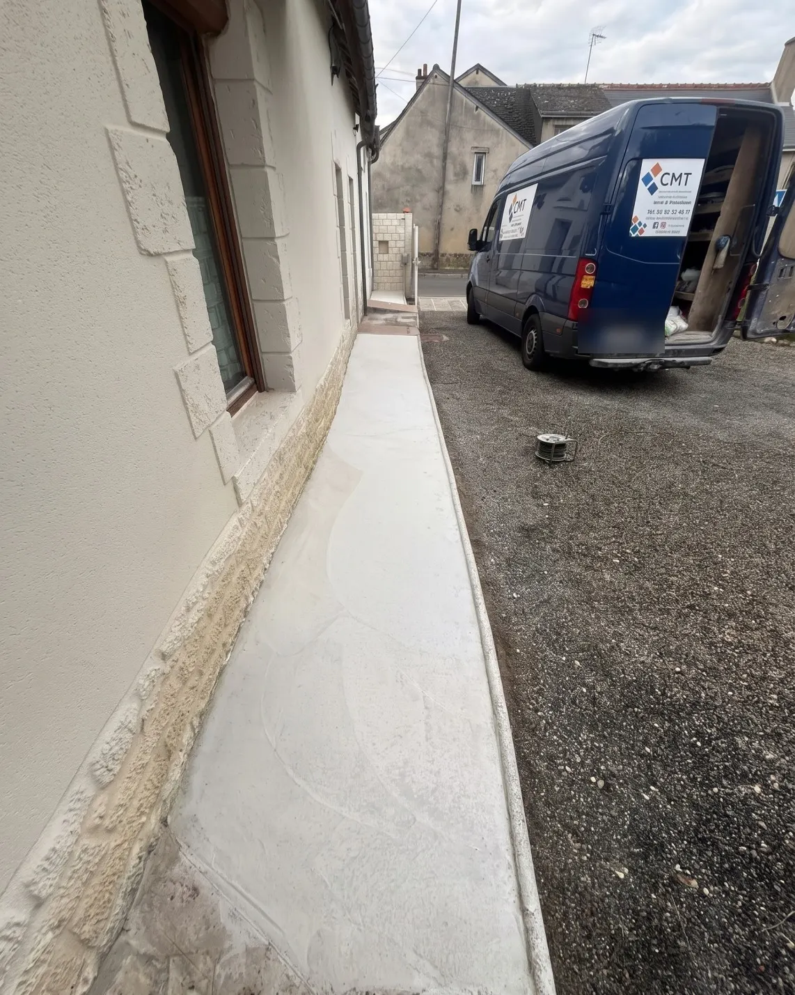 Chape tirée le long d'une maison, camion de l'entreprise au fond